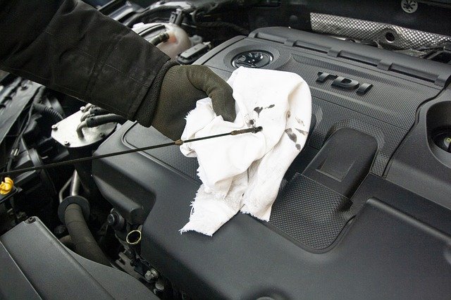 person checking car oil on white cloth
