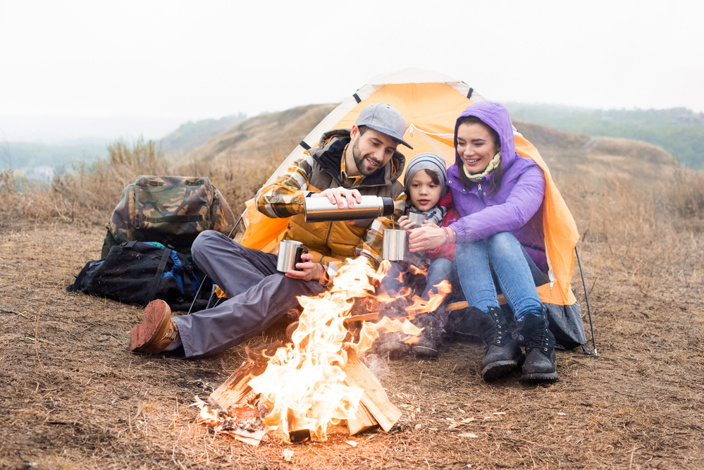 family of 3 sitting next campfire
